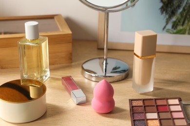 Photo of Makeup products and perfume on wooden dressing table