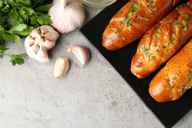 Photo of Plate of bread loaves with garlic and herbs on grey table, flat lay. Space for text