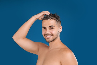 Photo of Young man washing hair on blue background