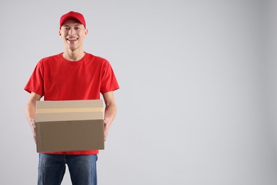 Photo of Happy courier with parcel on light grey background. Space for text