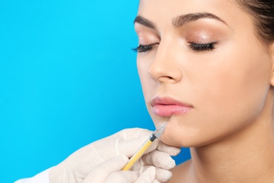 Photo of Young woman getting lips injection on color background, space for text. Cosmetic surgery