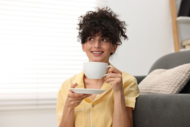 Photo of Beautiful young woman in stylish pyjama with cup of drink at home