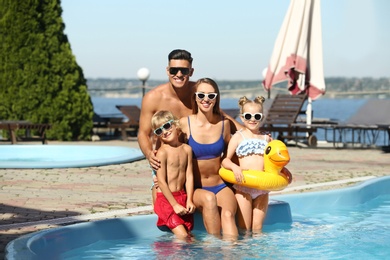 Photo of Happy family with inflatable ring at poolside on sunny summer day