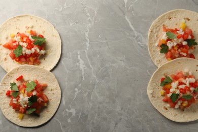 Photo of Delicious tacos with vegetables and parsley on grey marble table, top view. Space for text