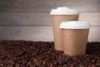 Photo of Coffee to go. Paper cups on roasted beans, closeup. Space for text