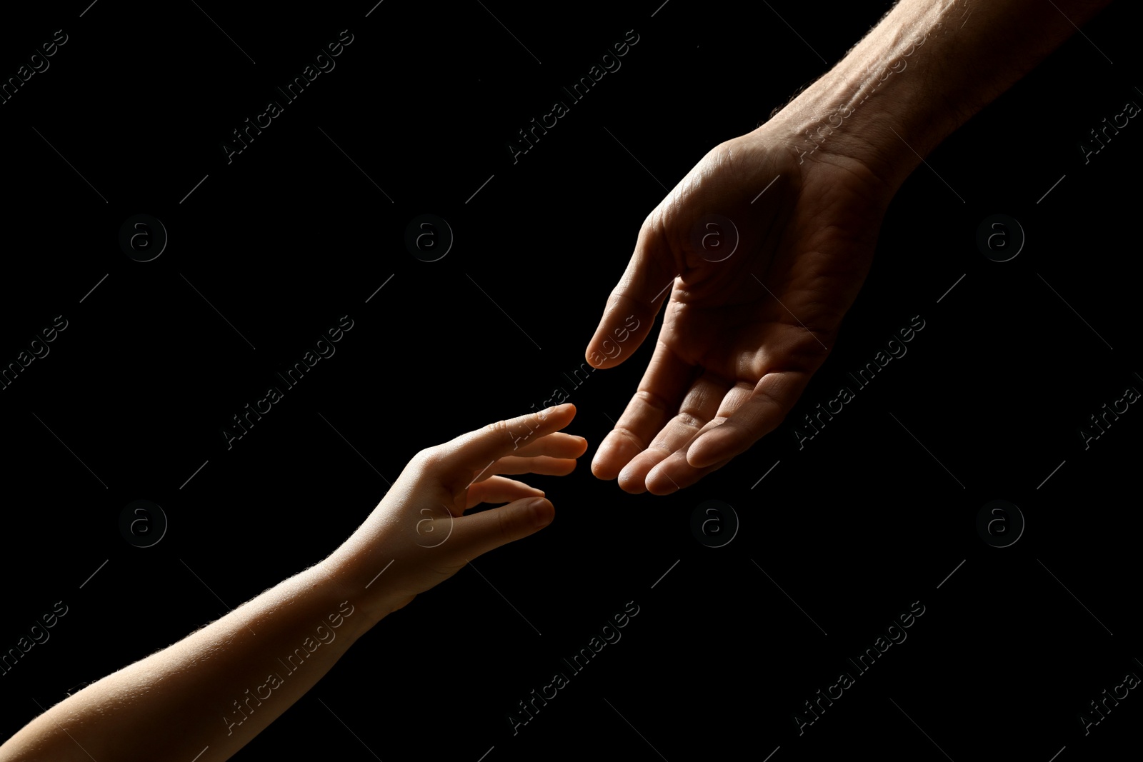 Photo of Man with child on black background, closeup of hands