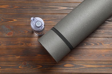 Photo of Yoga mat and bottle of water on wooden floor, flat lay