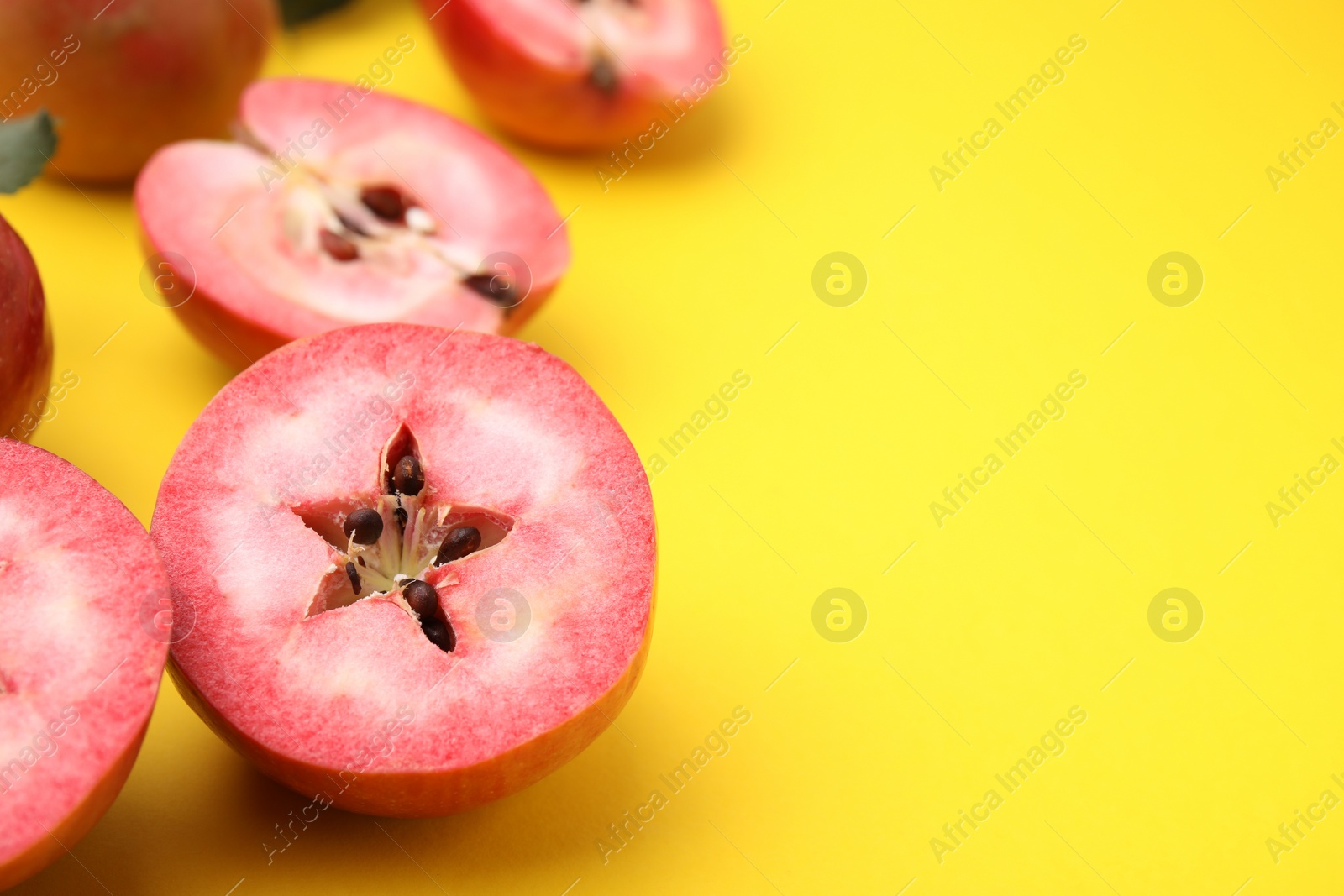 Photo of Tasty apples with red pulp on yellow background, closeup. Space for text