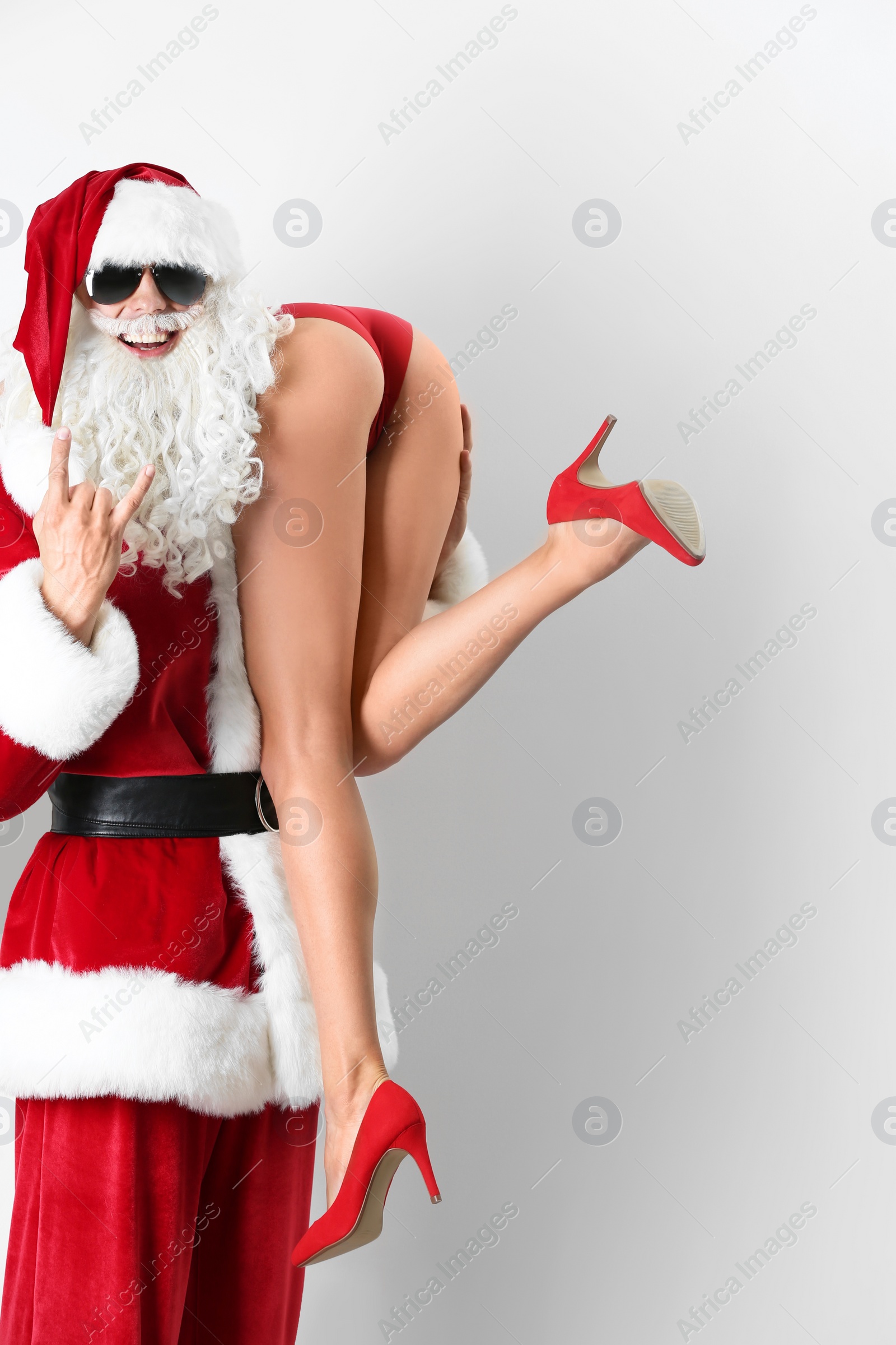 Photo of Young Santa Claus holding sexy naked woman on white background