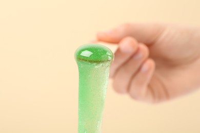 Woman holding spatula with hot depilatory wax on beige background, closeup