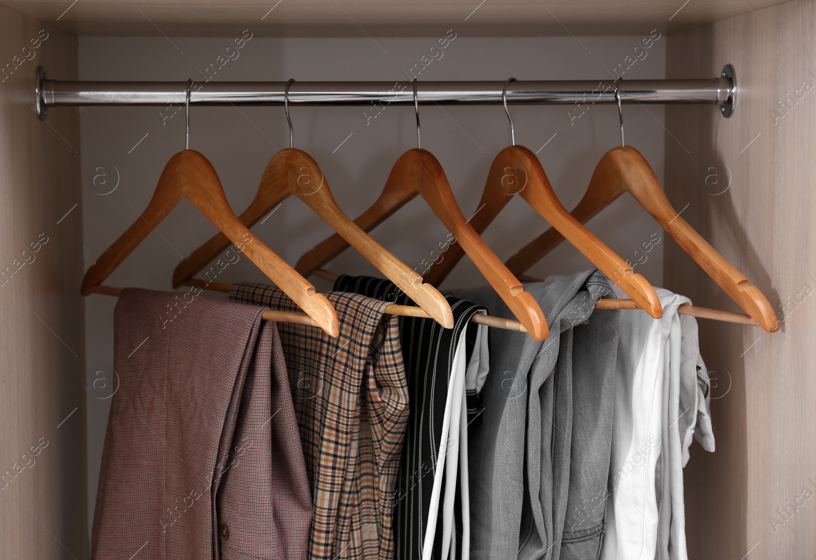 Photo of Collection of stylish pants on hangers in wardrobe closet