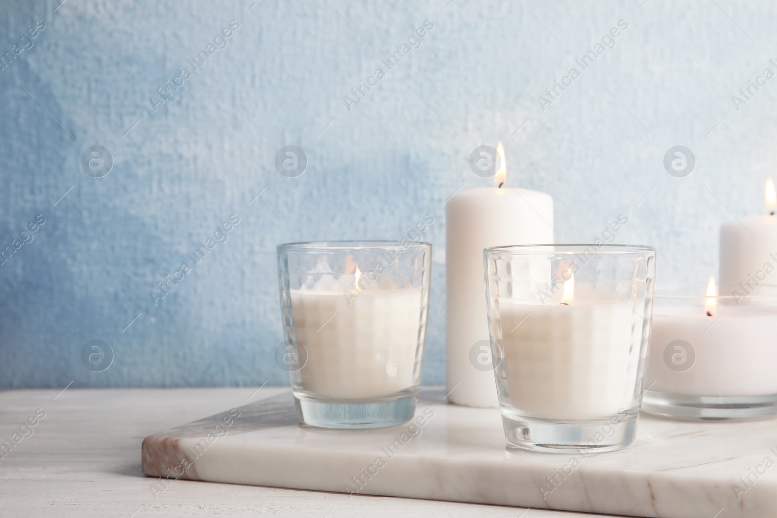 Photo of Burning candles on table against color background. Space for text