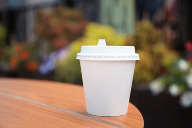 Cardboard cup with tasty coffee on table outdoors