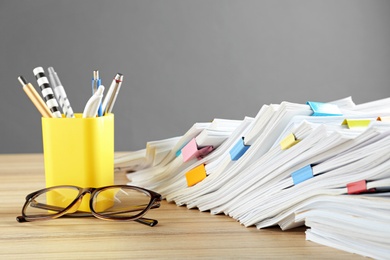 Stack of documents with binder clips and glasses on wooden table