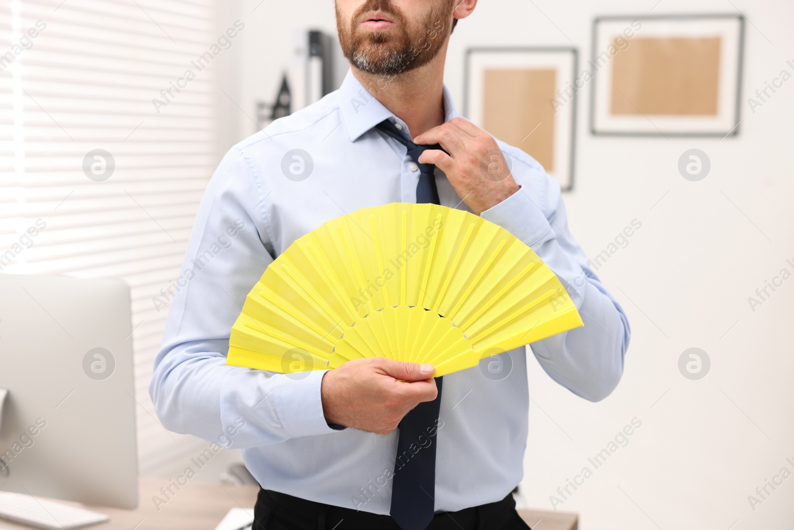 Photo of Businessman with yellow hand fan in office, closeup