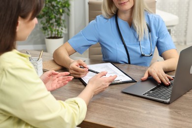 Photo of Doctor with results of laboratory test consulting pregnant patient in clinic, closeup