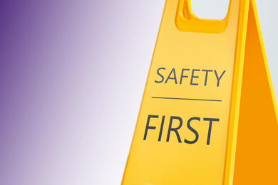 Sign with phrase SAFETY FIRST on color background, space for text 