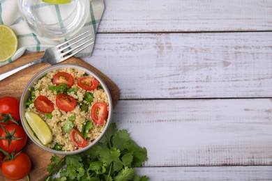 Delicious quinoa salad with tomatoes, parsley and lime served on white wooden table, flat lay. Space for text