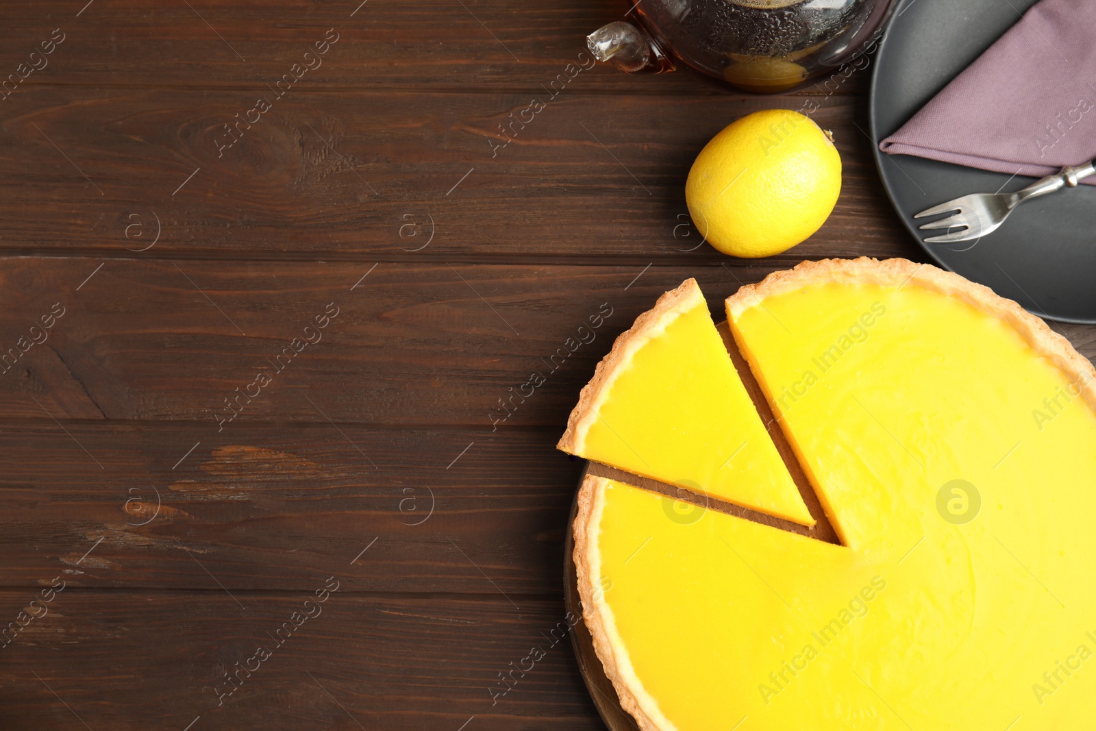 Photo of Delicious homemade lemon pie and tea on wooden table, flat lay. Space for text