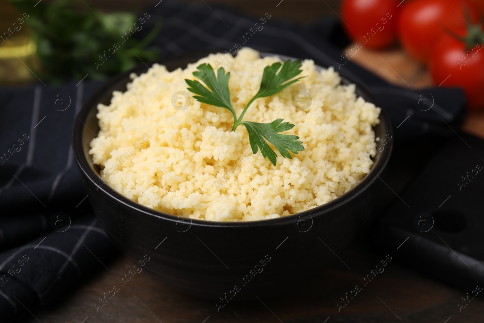 Photo of Tasty couscous and fresh parsley in bowl on table, closeup