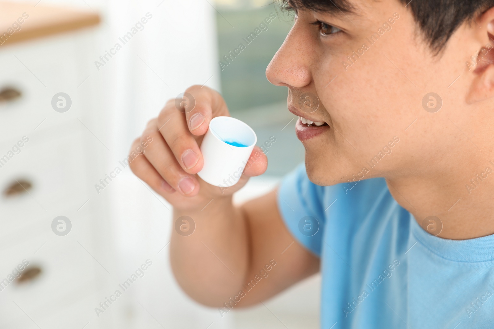 Photo of Man holding cap with mouthwash, closeup view. Teeth care