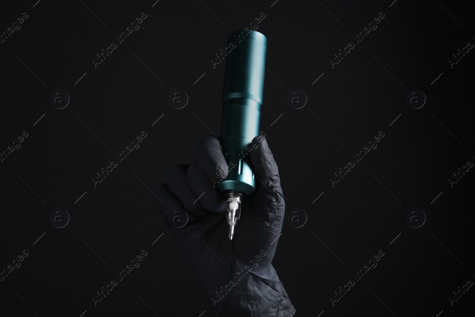 Photo of Professional tattoo artist with machine on black background, closeup