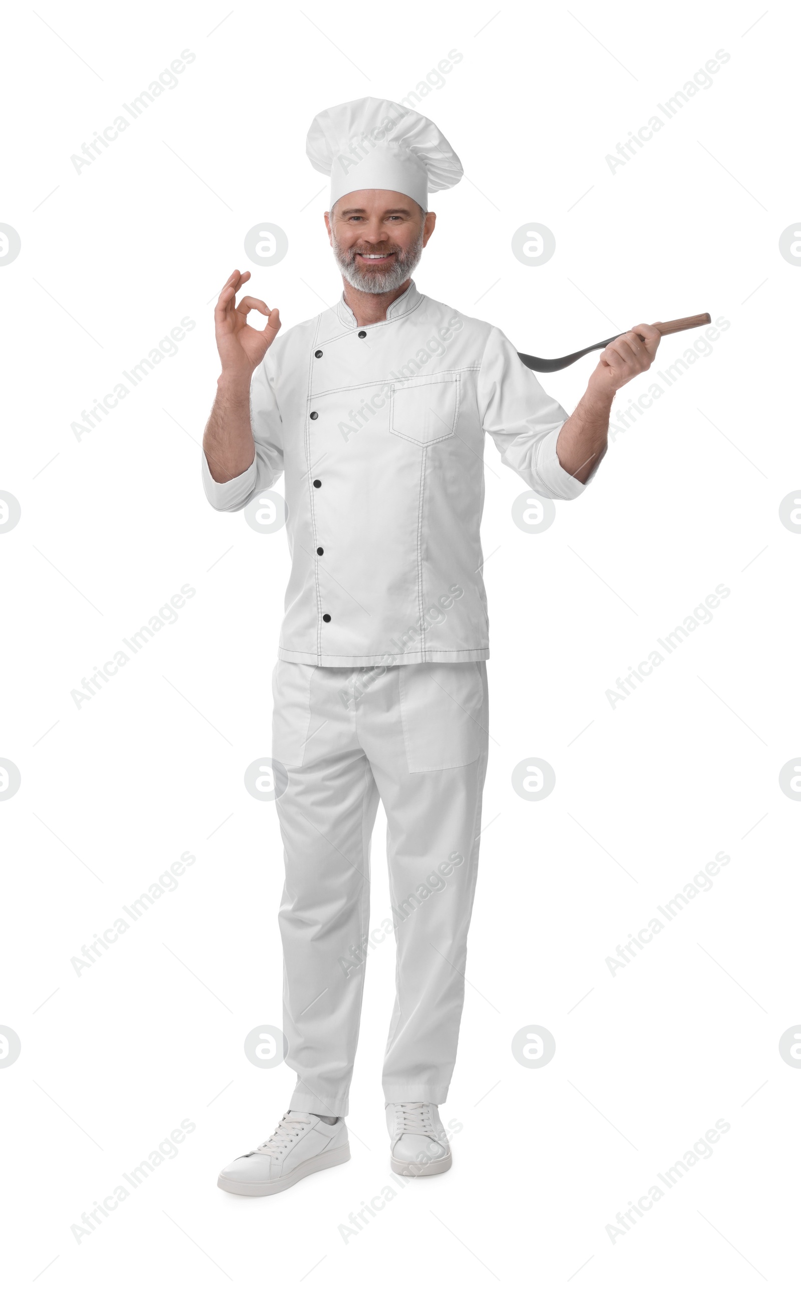 Photo of Happy chef in uniform with spoon showing OK gesture on white background