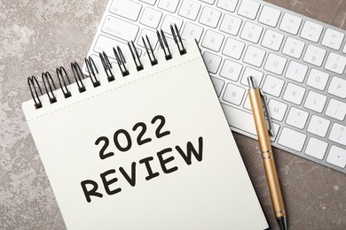 Image of Text 2022 Review written in notebook, pen and keyboard on grey marble table, flat lay