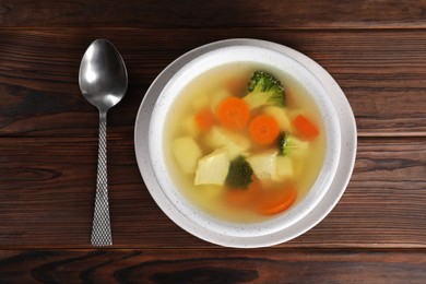 Tasty chicken soup with vegetables in bowl served on wooden table, top view