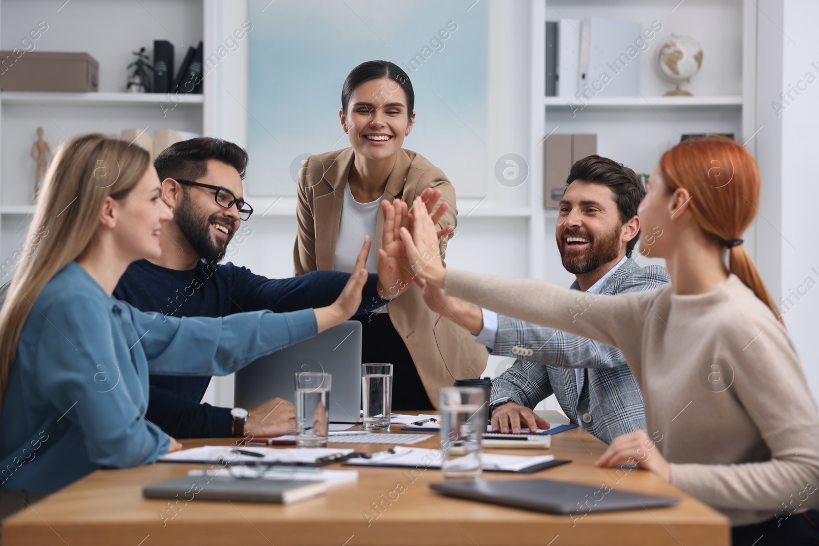 Photo of Team of employees joining hands in office