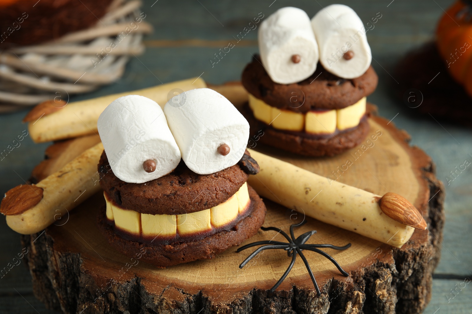 Photo of Delicious desserts decorated as monsters on stump, closeup. Halloween treat