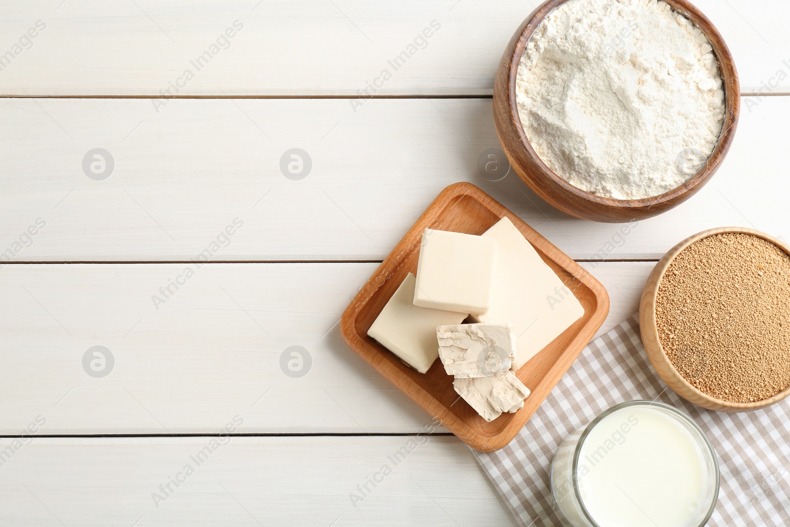 Photo of Yeast and dough ingredients on white wooden table, flat lay. Space for text