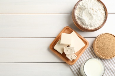 Yeast and dough ingredients on white wooden table, flat lay. Space for text