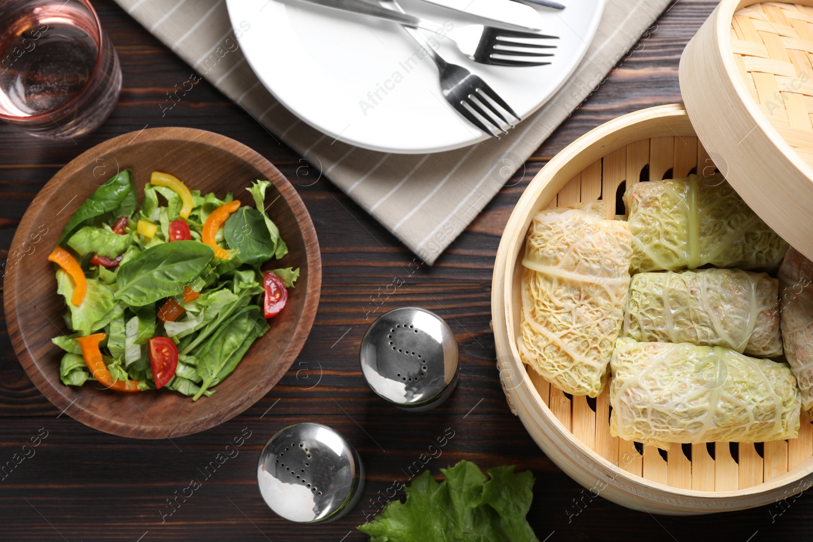 Photo of Delicious cabbage rolls served on dark wooden table, flat lay