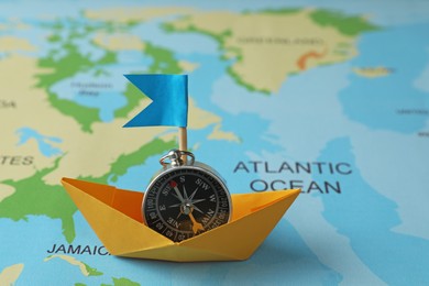 Photo of Yellow paper boat with compass on world map