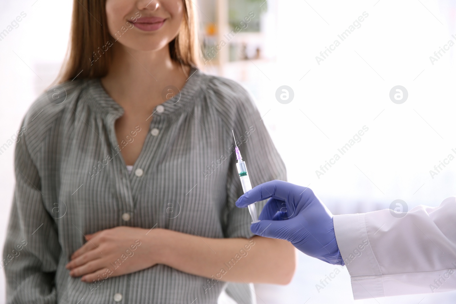 Photo of Doctor giving injection to pregnant woman in hospital, closeup. Vaccination concept