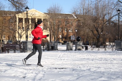 Photo of Happy woman running along park on winter day. Outdoors sports exercises