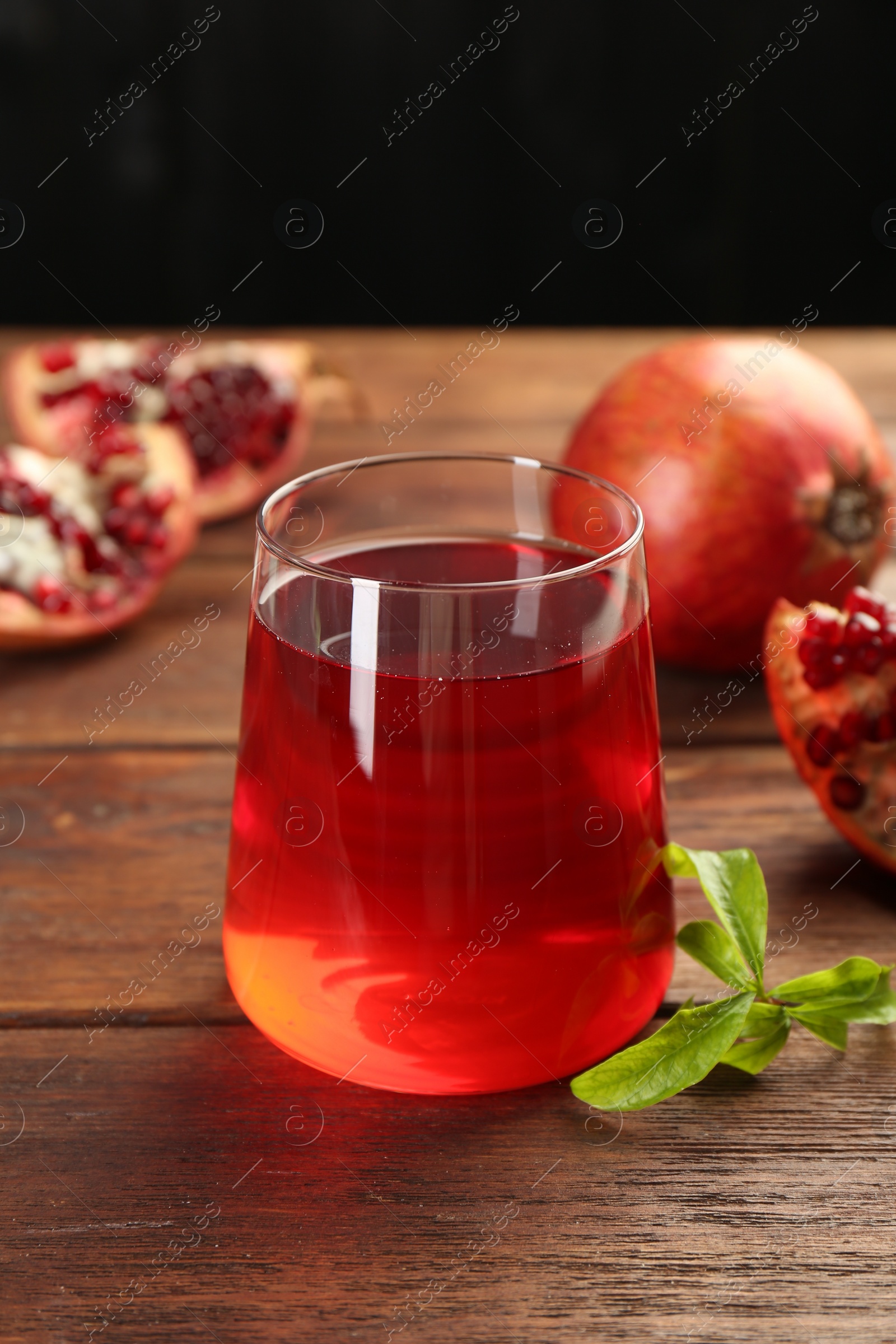 Photo of Tasty pomegranate juice in glass and fresh fruits on wooden table, closeup