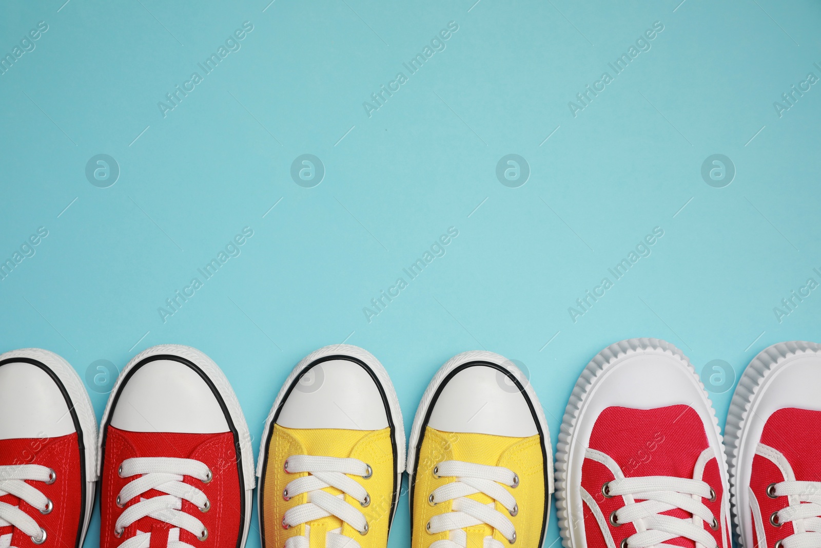 Photo of Different classic old school sneakers on light blue background, flat lay. Space for text