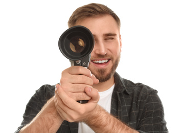 Young man with vintage video camera on white background, focus on lens