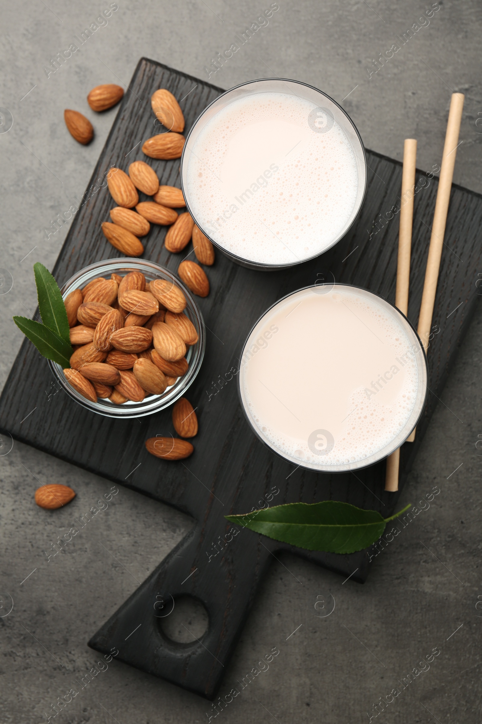 Photo of Glasses of almond milk and almonds on grey table, top view