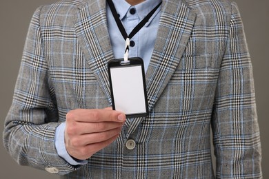 Man with blank badge on grey background, closeup