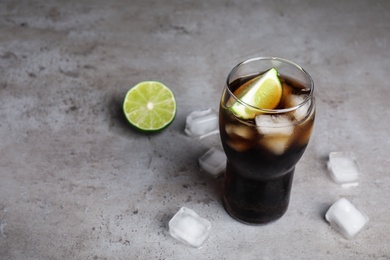 Photo of Refreshing soda drink, ice cubes and lime on grey table, space for text