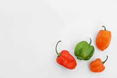 Photo of Different hot chili peppers on white background, flat lay. Space for text