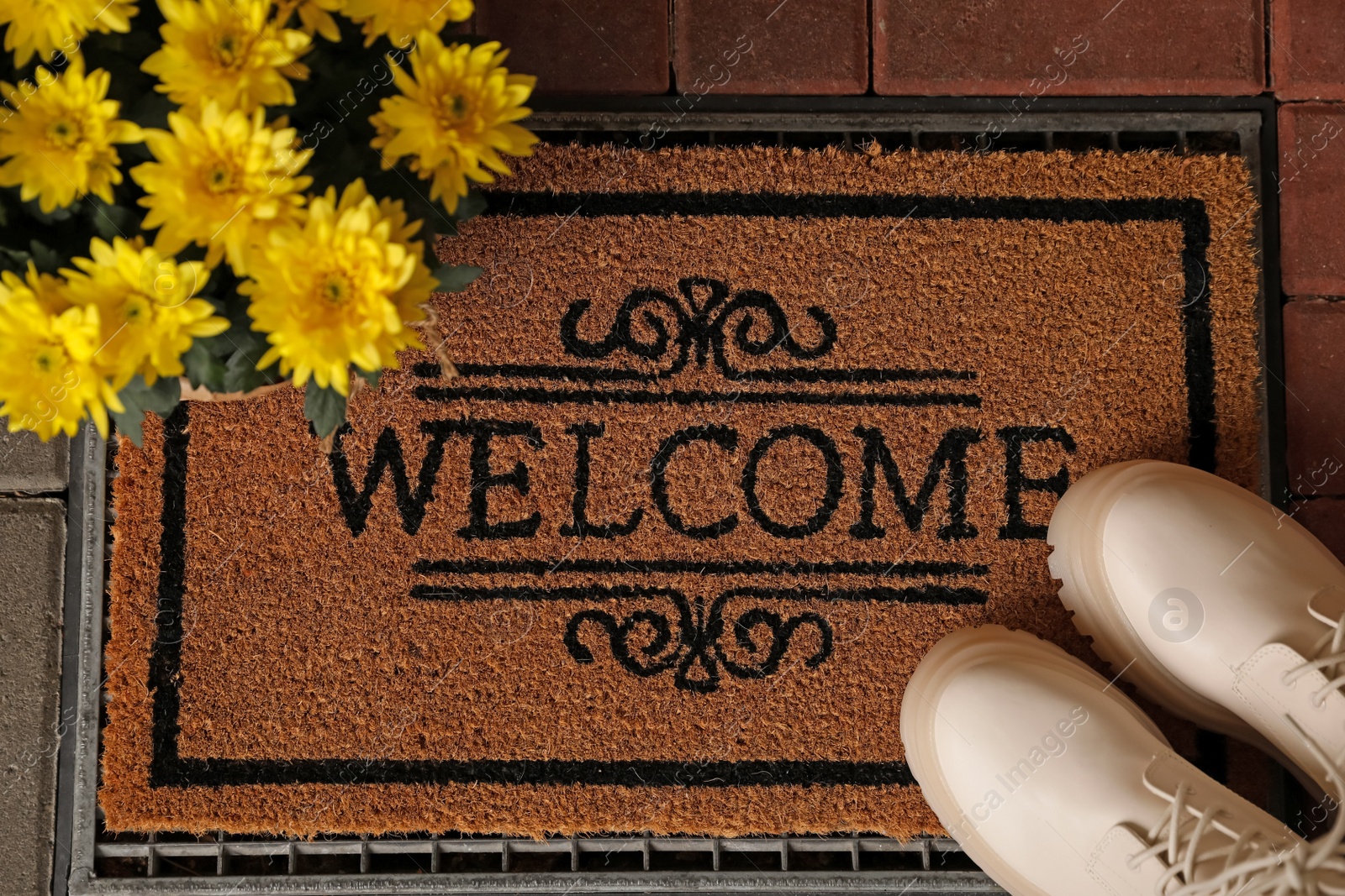 Photo of Door mat with word Welcome, stylish boots and beautiful flowers on floor, flat lay