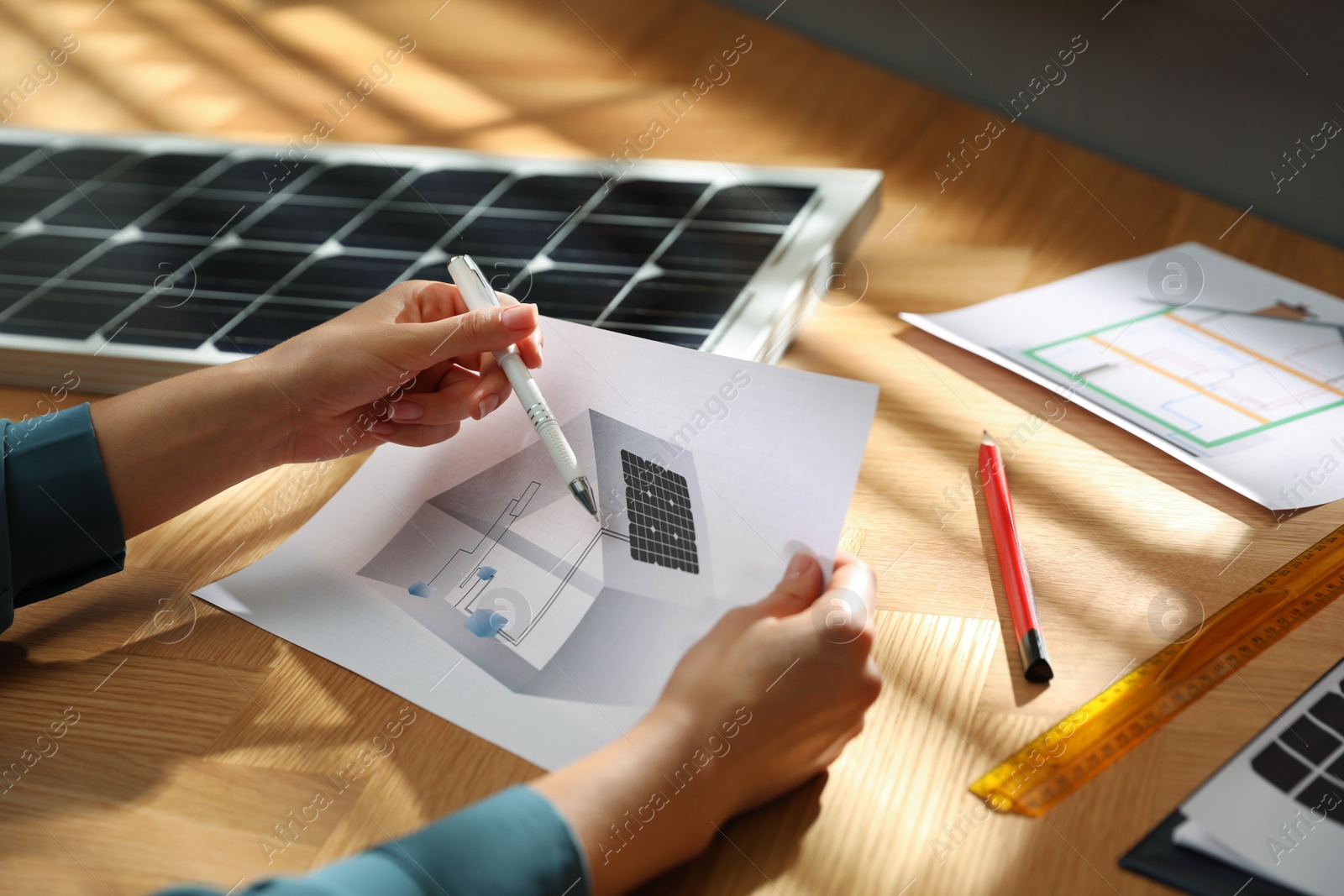 Photo of Woman working on house project with solar panels at table in office, closeup