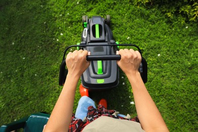 Photo of Above view of woman cutting grass with lawn mower in garden, closeup