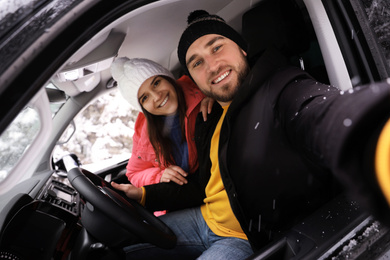 Young couple taking selfie in car. Winter vacation