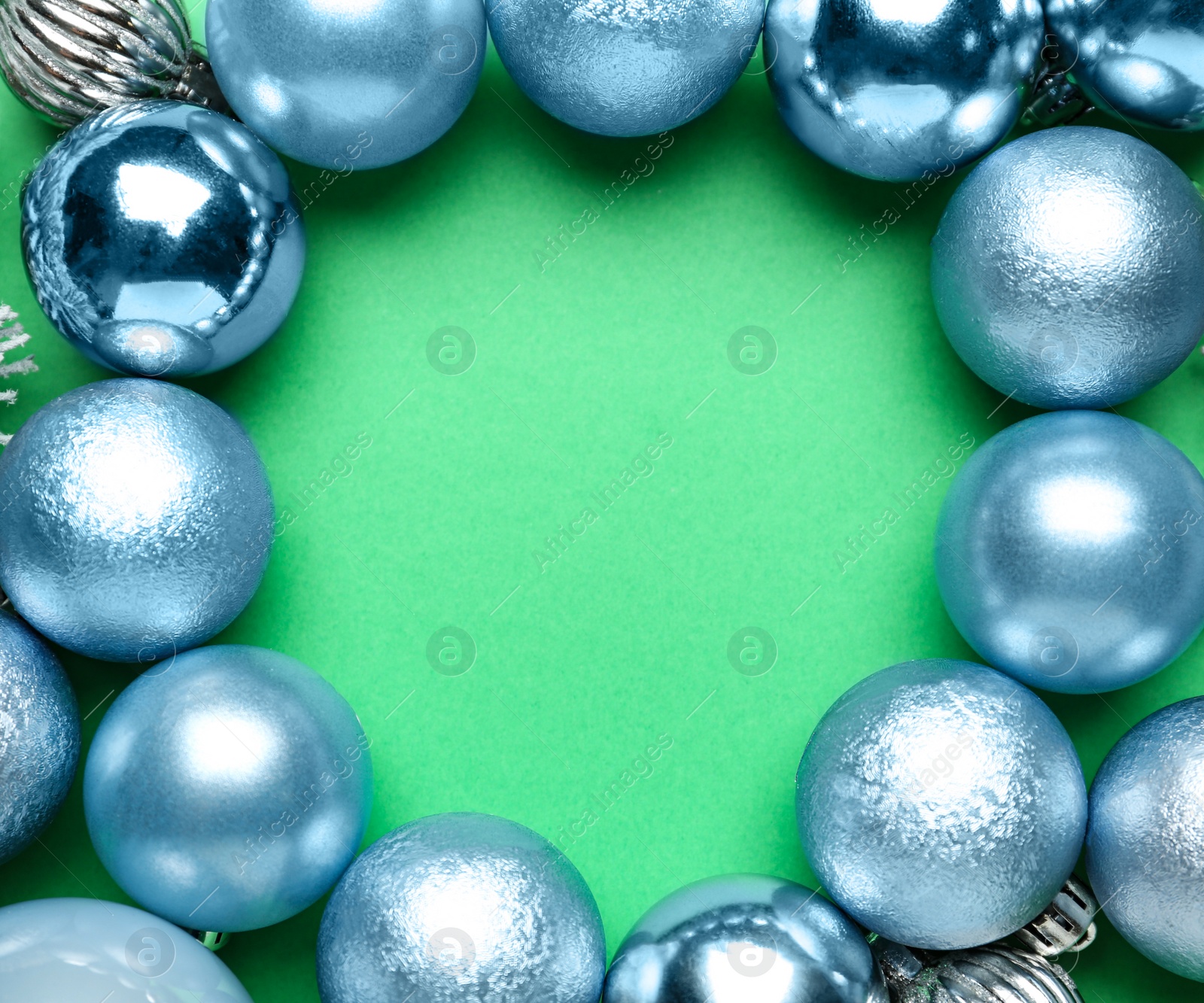 Photo of Frame of shiny Christmas balls and fir branches on green background, flat lay. Space for text