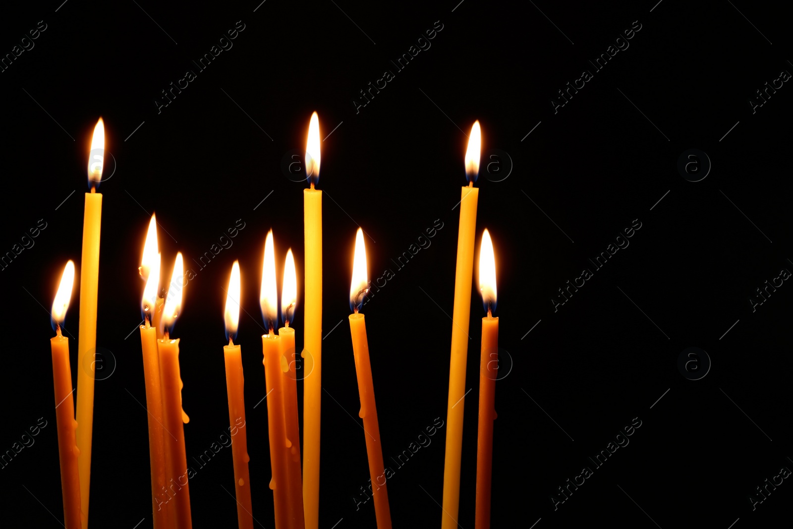 Photo of Many burning church candles on dark background. Space for text